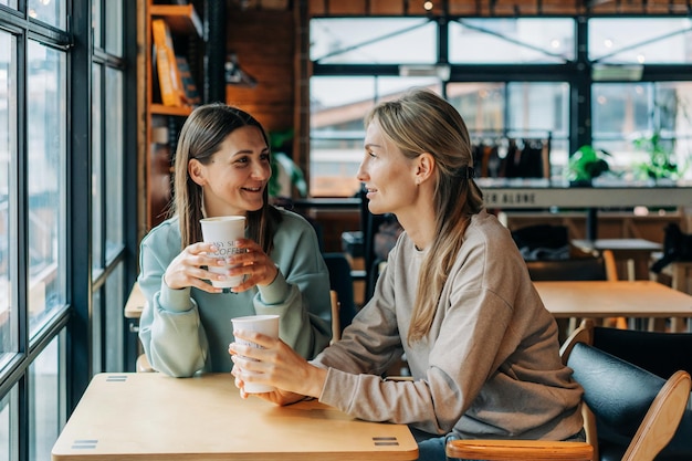 Duas mulheres sentadas numa cafeteria a falar e a beber café.