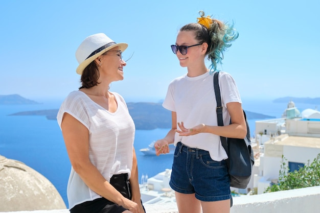 Duas mulheres sorridentes felizes, mãe e filha adolescente viajando juntas, viagens de luxo para a famosa ilha grega de Santorini