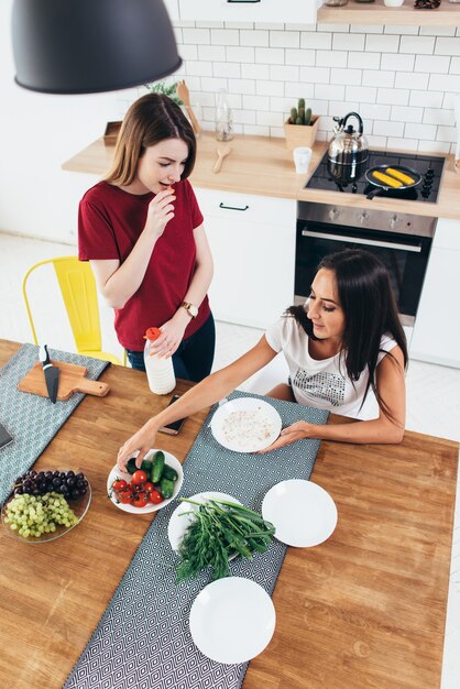 Duas mulheres tomando café da manhã em casa na cozinha.