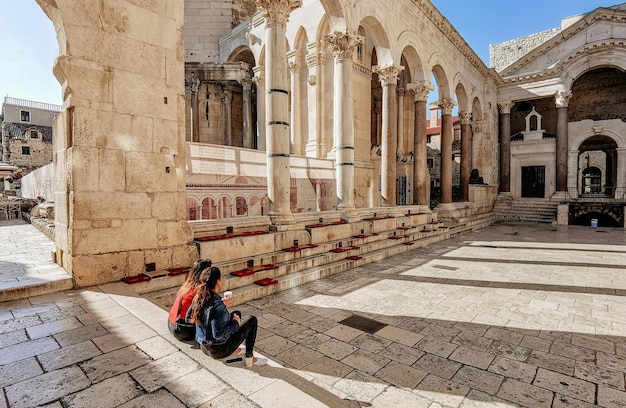 Duas mulheres tomando café nos degraus do Peristilo no palácio de Diocleciano em Split, Croácia.