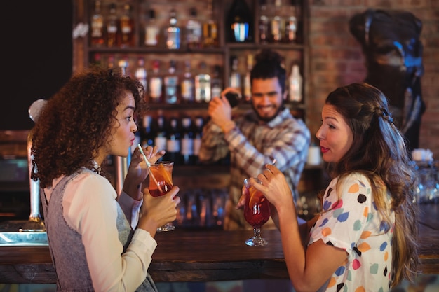 Duas mulheres tomando coquetéis no balcão