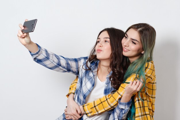 Duas mulheres tomando selfie com telefone celular em branco