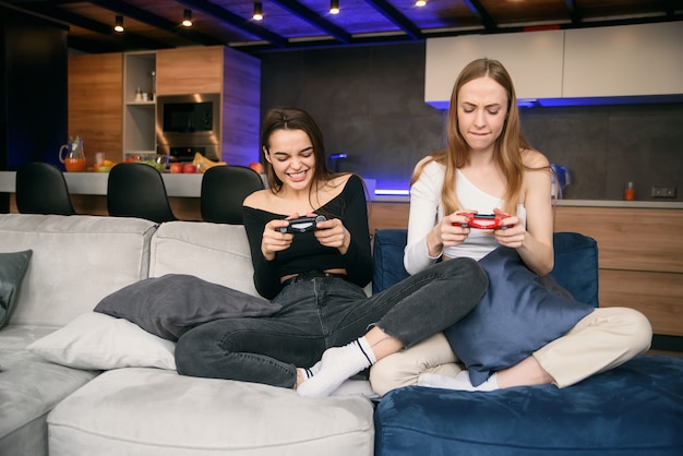 Duas namoradas apaixonadas jogando jogos de computador em casa enquanto estão em quarentena. Isolamento doméstico pandêmico mundial. Aproveitando o tempo para passar o lazer.