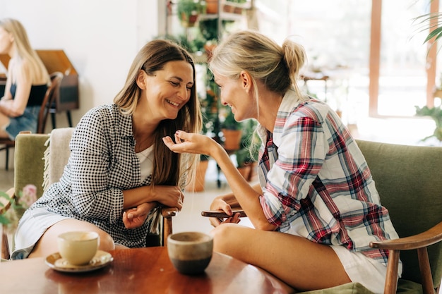 Duas namoradas elegantes estão falando enquanto estão sentadas em um café