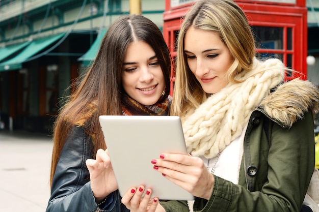 Duas namoradas jovens em uma viagem juntos e usando o tablet.