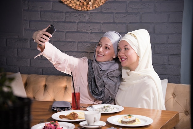 Duas namoradas muçulmanas são fotografadas em uma mesa em um café