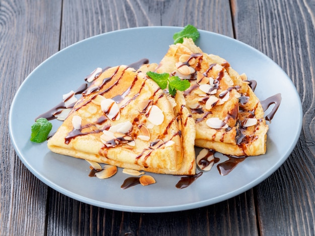 Duas panquecas com calda de chocolate, flocos de amêndoa no prato