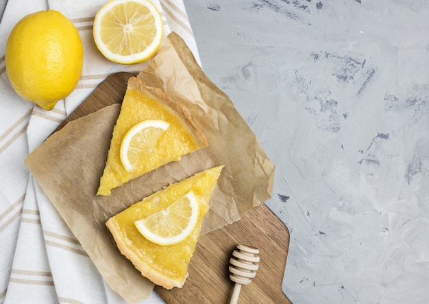 Duas partes de torta de limão com fatia de close up dos limões no fundo de pedra, copiam o espaço.