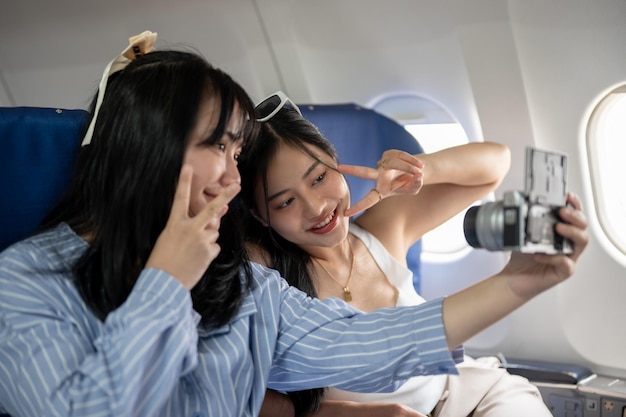 Duas passageiras asiáticas felizes estão tirando uma selfie juntas durante o voo