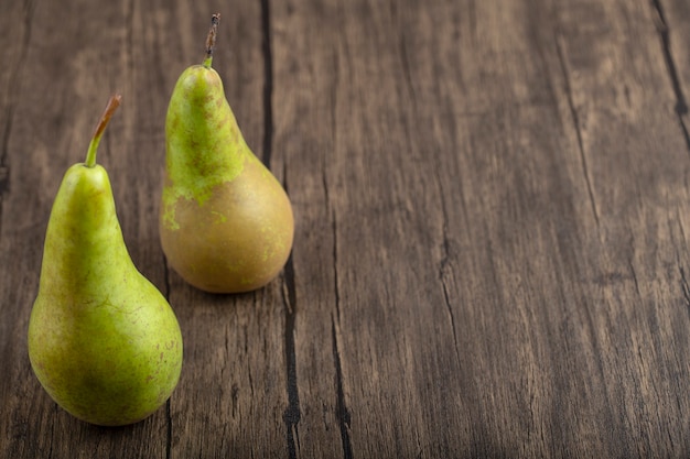 Duas peras verdes deliciosas maduras em fundo de madeira.