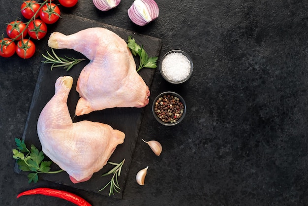 duas pernas de frango cru com especiarias e ervas em um fundo de pedra com espaço de cópia para o seu texto