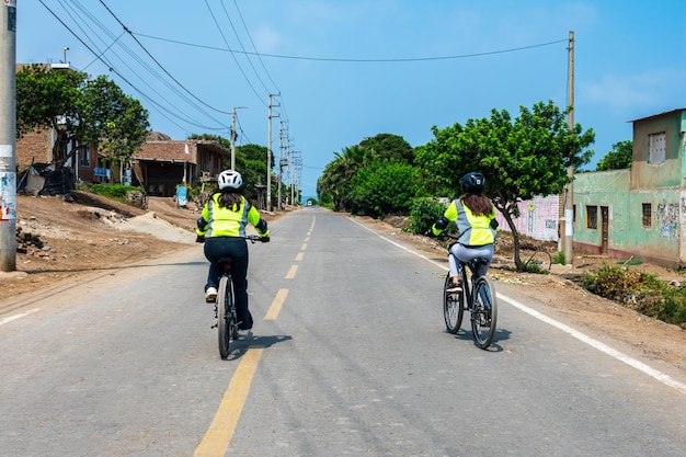 Duas pessoas andando de bicicleta em uma estrada com uma placa que diz 'bicicleta à direita'