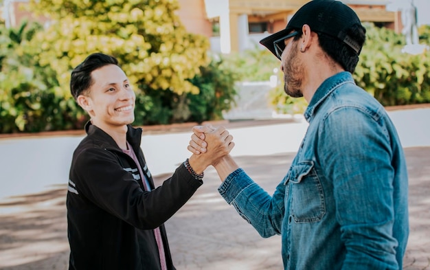 Duas pessoas apertando as mãos na rua Dois amigos adolescentes apertando as mãos uns aos outros ao ar livre Conceito de dois amigos cumprimentando uns aos outros com aperto de mão na rua