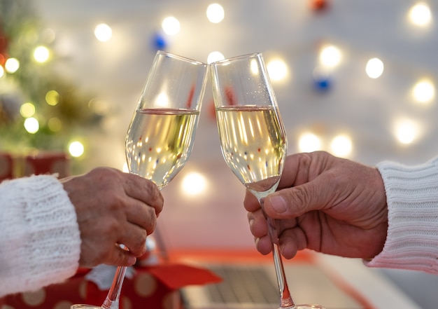 Duas pessoas brindando com uma taça de vinho espumante comemorando o natal