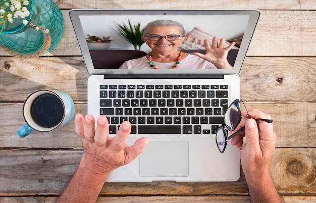 Duas pessoas em videochamada com laptop. Mulher sênior sorridente