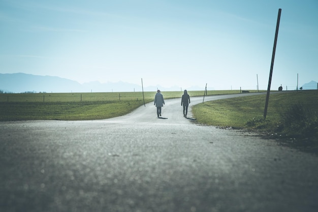 Duas pessoas estão andando na estrada asfaltada