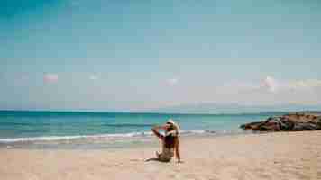 Foto duas pessoas estão na praia, uma delas está a usar um chapéu.