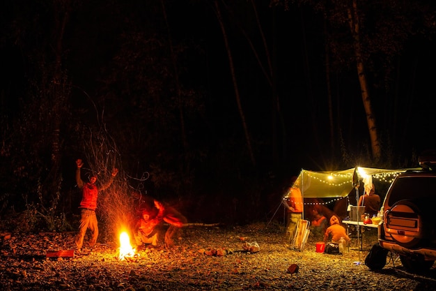 Foto duas pessoas estão se divertindo jogando fantasmas em seu acampamento na floresta à noite