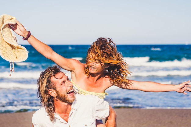 Duas pessoas felizes, se divertindo juntos e sorrindo na praia. Férias ao ar livre juntos.