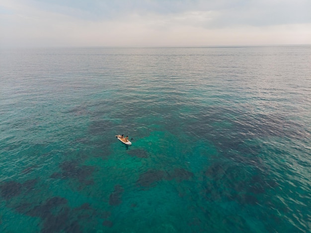 Duas pessoas na prancha de surf no mar com água azul clara