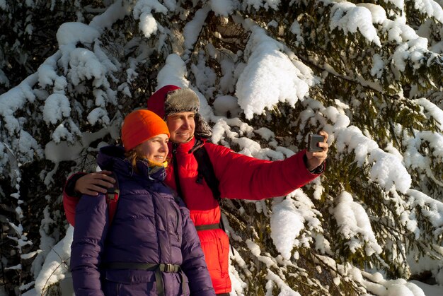 Duas pessoas tiram fotos de si mesmas com um smartphone no inverno