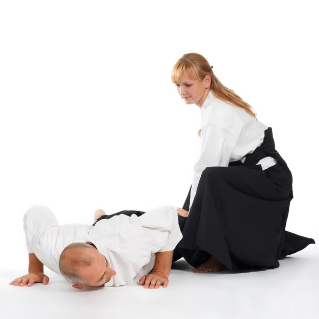 Duas pessoas um homem e uma mulher praticam aikido no tapete isolado no fundo branco