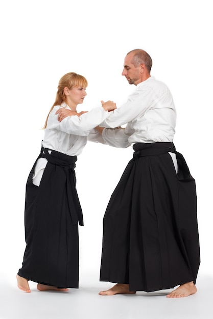 Duas pessoas um homem e uma mulher praticam aikido no tapete isolado no fundo branco