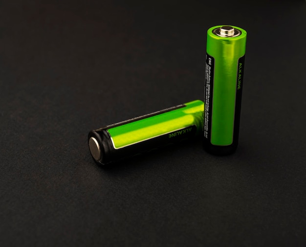 Duas pilhas AA verdes isoladas em um fundo preto. acumuladores