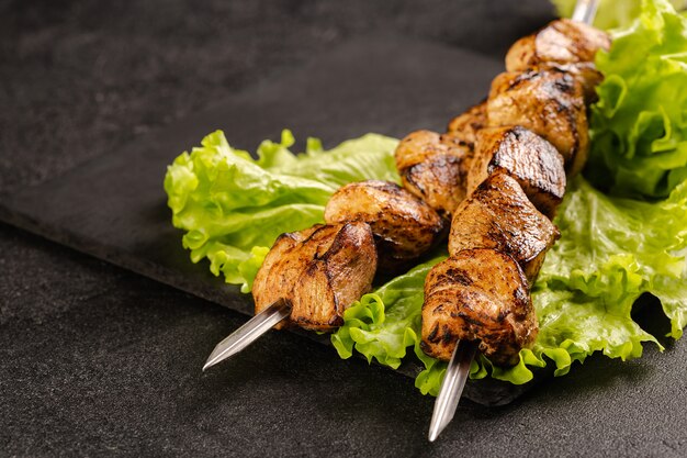 Duas porções de shish kebab em um prato de pedra com salada.