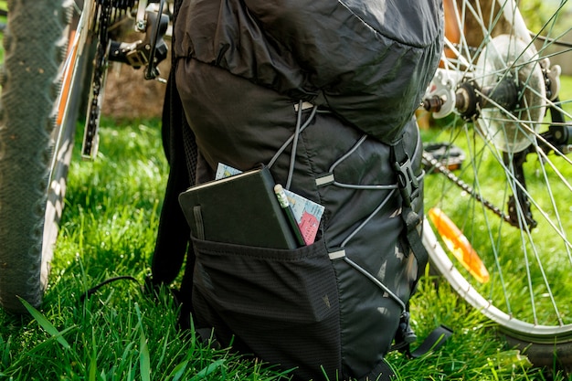 Duas rodas de bicicleta e equipamento turístico de mochila preta com fundo verde externo, vista traseira.