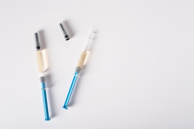 Duas seringas com medicamento para injeção em um fundo branco