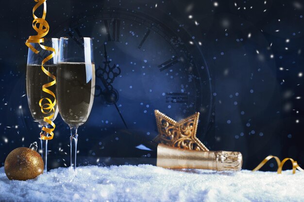 Duas taças de vinho com relógio de champanhe e enfeites de Natal em um fundo preto com reflexão Feliz Natal e feliz ano novo