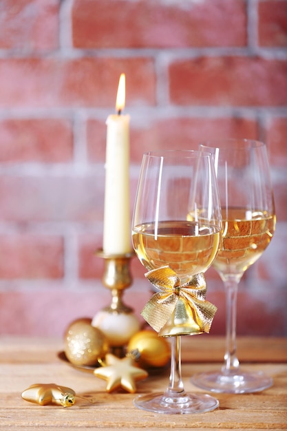 Duas taças de vinho com velas e brinquedos de natal na superfície da parede