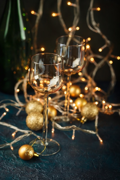 Duas taças de vinho e bolas de Natal douradas contra luzes douradas desfocadas.