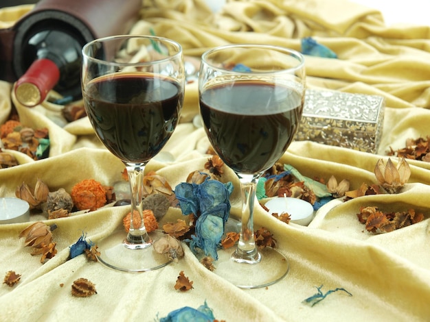 Duas taças de vinho tinto sobre uma mesa com uma garrafa de vinho ao fundo.