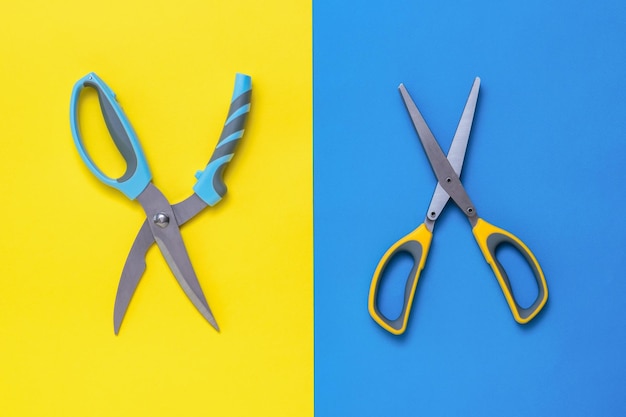 Duas tesouras de cozinha em um fundo azul e amarelo Dispositivos para cortar salada