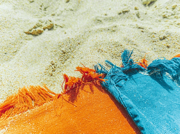 Foto duas toalhas na areia da praia, laranja e azul.