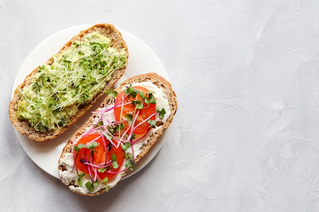 Duas torradas com tomates abacate e microgreens comida saudável aperitivo caseiro saboroso ou café da manhã