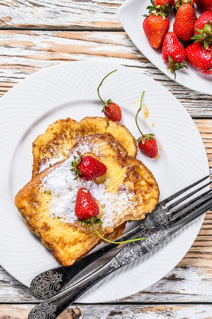 Foto duas torradas francesas fritas com açúcar de confeiteiro e morangos