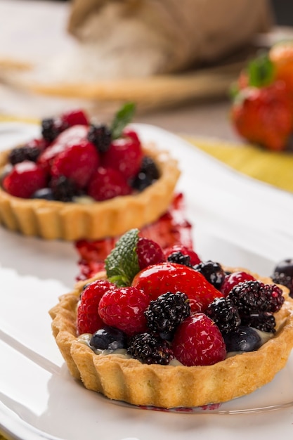 Duas tortas de frutas com framboesas, mirtilos e amoras em um prato sobre a mesa.