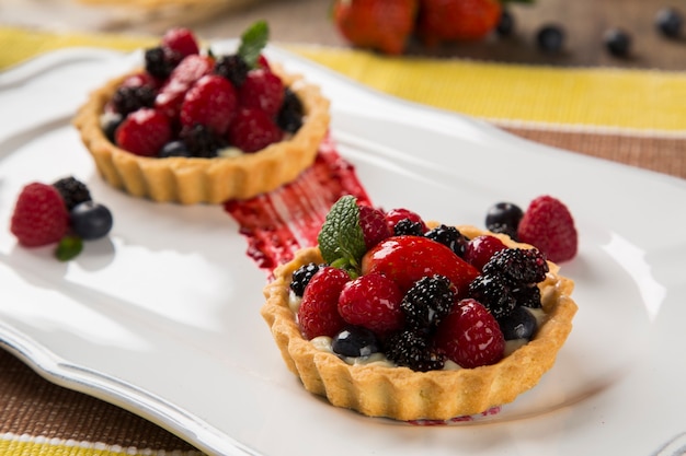 Duas tortas de frutas com framboesas, mirtilos e amoras em um prato sobre a mesa.