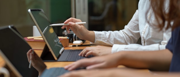 Duas trabalhadoras consultoria em seu projeto enquanto trabalhava com tablet na mesa de madeira