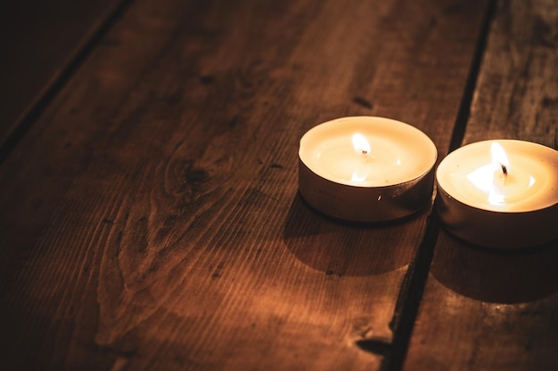duas velas acesas em cima de uma mesa de madeira marrom, copie o espaço.