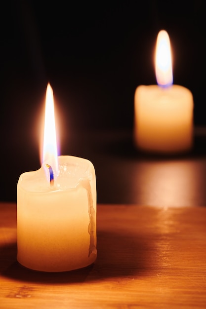 Duas velas acesas na mesa na escuridão da noite. Chama da esperança e da memória. Close-up vista com espaço de cópia.