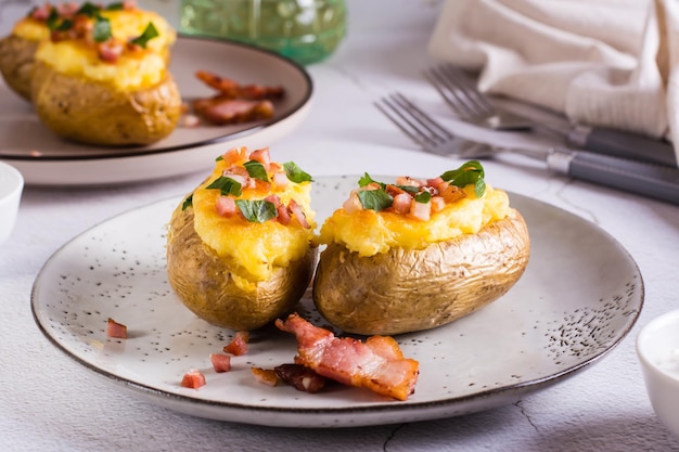 Duas vezes batatas assadas com bacon e queijo num prato sobre a mesa Jantar caseiro