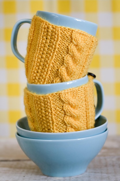 Duas xícaras azuis em suéter amarelo em um fundo de tecido