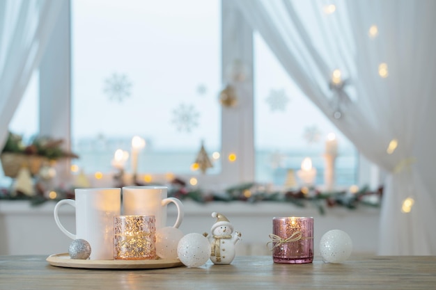 Duas xícaras brancas com enfeites de natal na janela do fundo