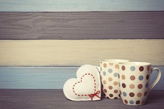 Foto duas xícaras com coração de feltro na cor de fundo de madeira