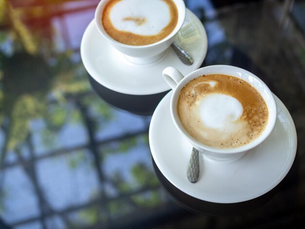 Duas xícaras de café cerâmicas brancas na mesa de vidro