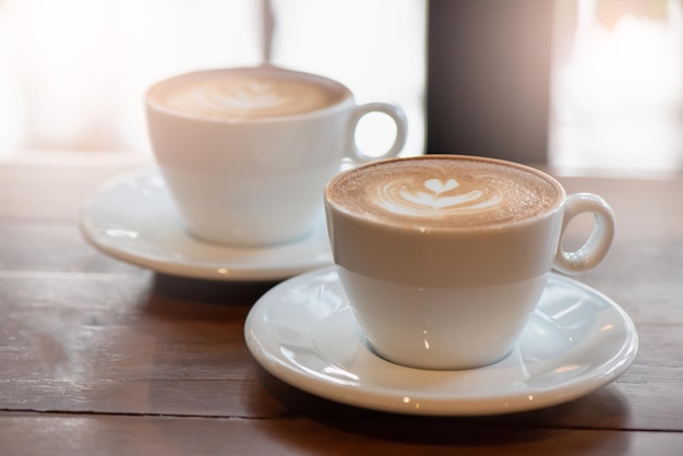 Duas xícaras de café com leite ou cappuccino na mesa de madeira